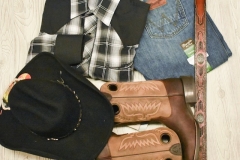 A bundle of western clothing, including a western hat, shirt, pants and belt.