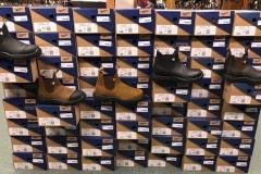 A stack of boot boxes with boots infront of them.