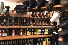 A shelve that is containing workboots and western hats.